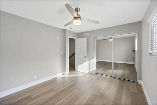 A room with a ceiling fan and a sliding glass door leading to a balcony.