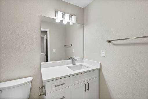 A white bathroom with a sink, mirror, and bathtub.