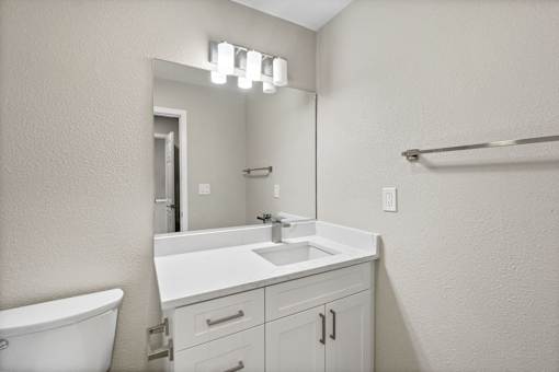 A white bathroom with a sink, mirror, and bathtub.