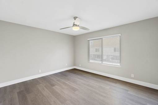A room with a ceiling fan and a window with blinds.