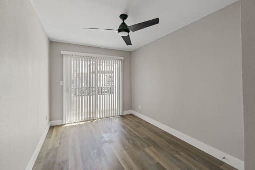 an empty living room with sliding glass doors and a ceiling fan at Ocean Breeze Terrace Apartment, Huntington Beach, 92648