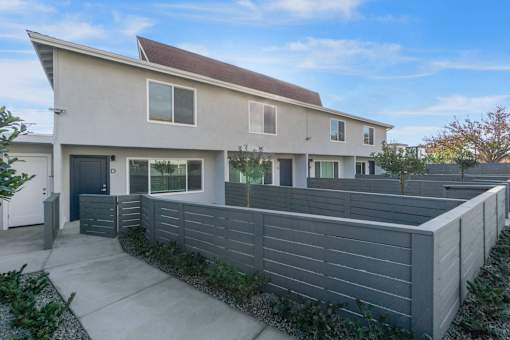 A modern house with a grey fence and a brown roof.