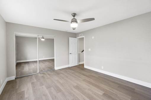 A room with a ceiling fan and sliding doors.