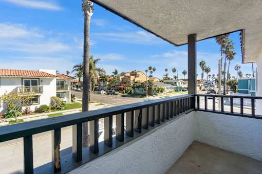 a balcony with a view of the street and palm trees at Ocean Breeze Terrace Apartment, Huntington Beach, 92648