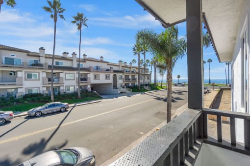 the view of the street from the balcony of an apartment building with palm trees at Ocean Breeze Terrace Apartment, Huntington Beach
