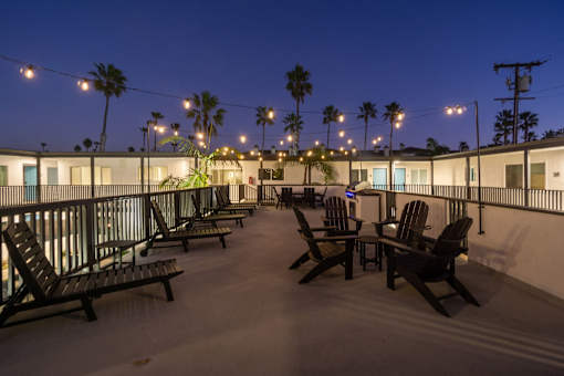 A patio with chairs and a table is lit by string lights at Ocean Breeze Terrace Apartment, Huntington Beach, CA