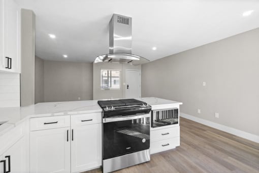 a kitchen with white cabinets and a stove and a hood at Ocean Breeze Terrace Apartment, Huntington Beach, CA, 92648