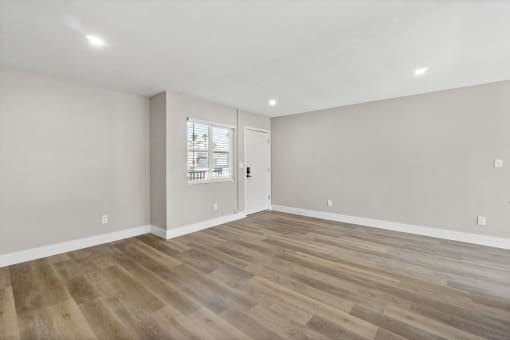the living room of a new home with white walls and wood floors at Ocean Breeze Terrace Apartment, Huntington Beach, CA