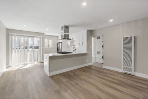 a renovated living room and kitchen with white walls and wood floors at Ocean Breeze Terrace Apartment, Huntington Beach