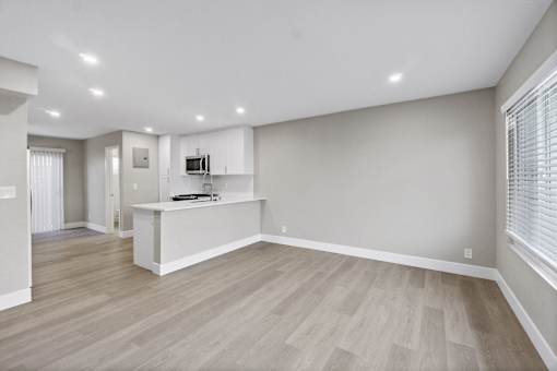 A spacious living room with a white kitchen island and light wood flooring.