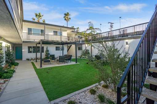 A patio with a table and chairs is surrounded by a green lawn. at Ocean Breeze Terrace Apartment, Huntington Beach, 92648