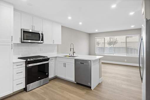 A modern kitchen with white cabinets and stainless steel appliances.