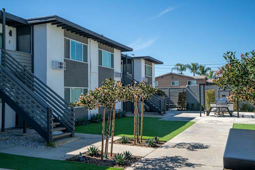 A sunny day at a modern apartment complex with a staircase leading to the second floor.