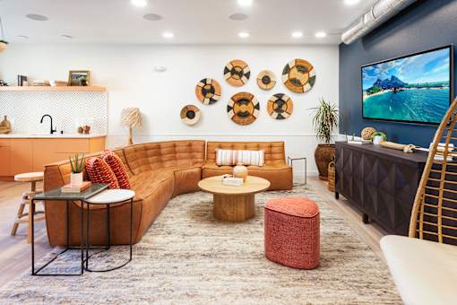 A living room with a brown sofa, a coffee table, and a TV on the wall. at The Reserve La Mirada, La Mirada, 90638