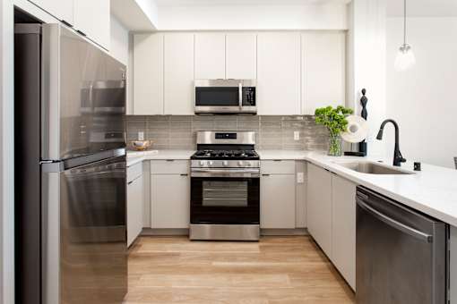 A modern kitchen with stainless steel appliances and white cabinets. at The Reserve La Mirada, La Mirada