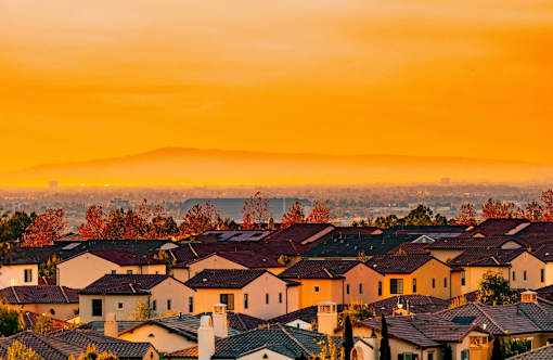 A sunset view of a neighborhood with houses and trees.