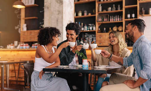 Four people are sitting around a table in a cafe.