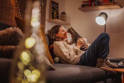 A woman is sitting on a couch holding a cat.