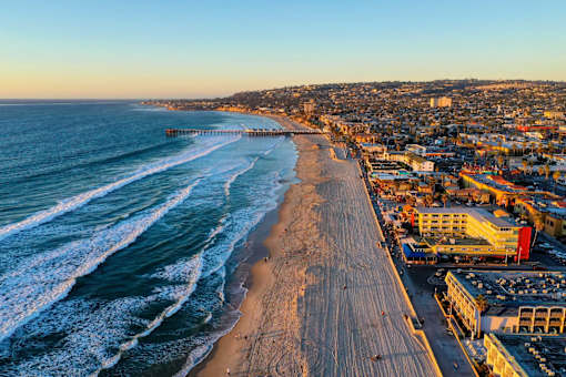 A beach with waves coming in and buildings in the background.
