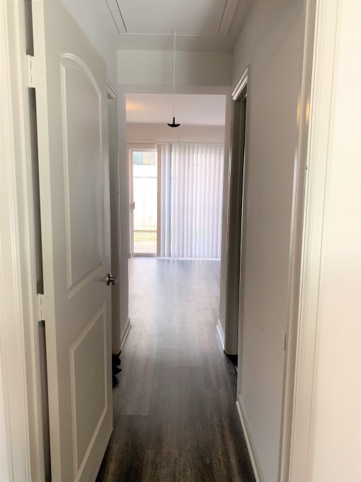 a look down the hallway of a new home with white walls and wood floors