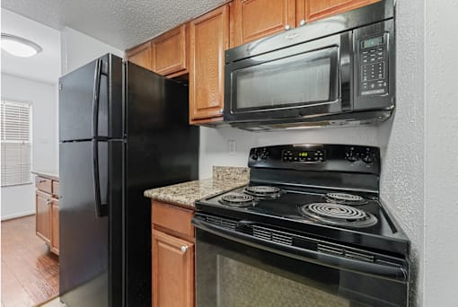 A black refrigerator and microwave in a kitchen.