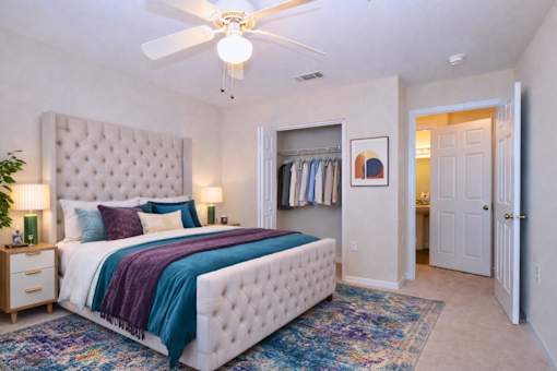 Master bedroom with tufted bed and ceiling fan at Walnut Ridge Apartments, Raleigh, North Carolina