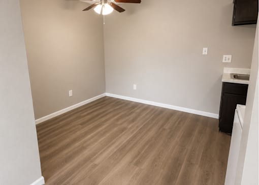 A room with a ceiling fan and wooden flooring.