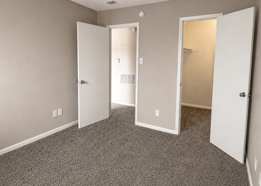 A room with carpeted floor and three open doors.