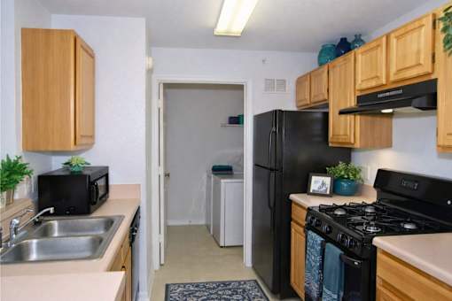 Galley kitchen with black appliances and wood cabinetry at Walnut Ridge Apartments, Raleigh