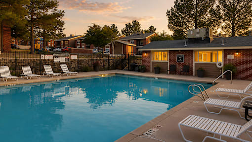 Swimming pool with lounge chairs at sunset at Las Lomas Apartments, Texas