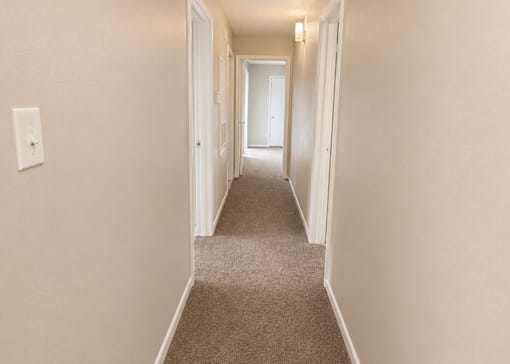 A long hallway with carpeted floors and white walls.