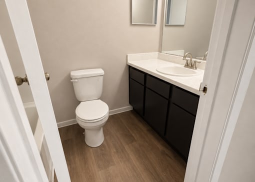 A white toilet sits in a bathroom next to a sink.