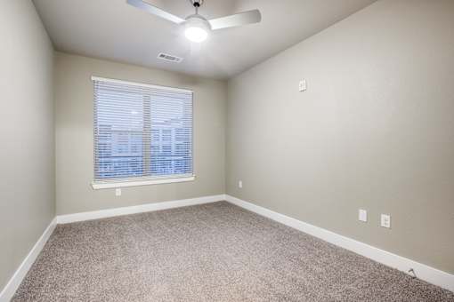 A room with a ceiling fan and carpeted floor.