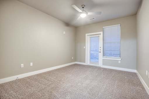 A room with a carpeted floor and a ceiling fan.