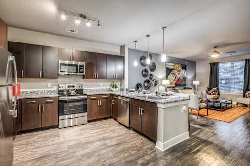 A modern kitchen with dark wood floors and stainless steel appliances.