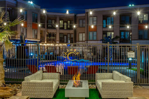 A pool area with a fire pit and lounge chairs.