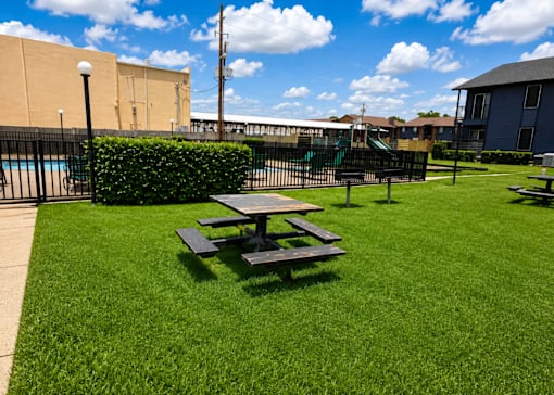 A picnic table sits on a green lawn.