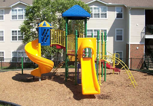 Outdoor playground with bright yellow slides and green equipment at Walnut Ridge Apartments, Raleigh, NC