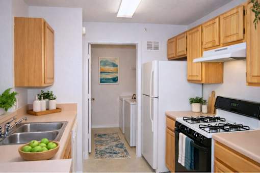 Galley kitchen with gas range and white refrigerator at Walnut Ridge Apartments, Raleigh, North Carolina