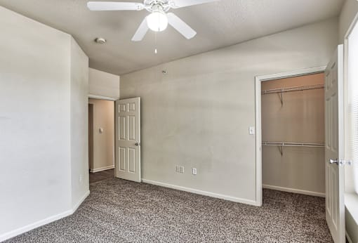 A bedroom with a closet and a ceiling fan in Arlington, TX.