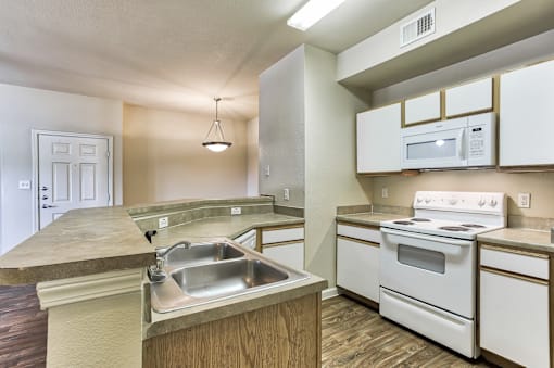 A kitchen with white appliances and a sink in Arlington, TX.