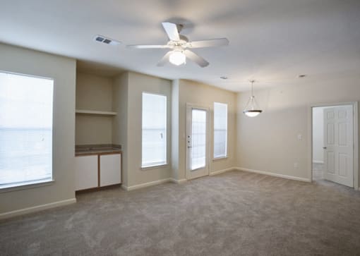 A spacious room with a ceiling fan and carpeted floor in Arlington, TX.