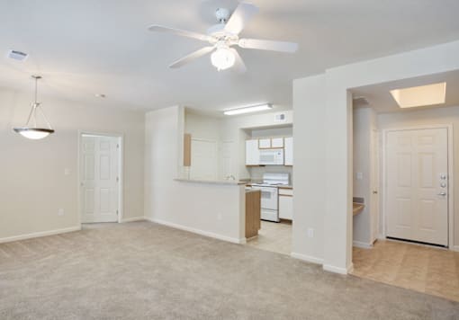 A spacious room with a ceiling fan and a kitchen area in the background in Arlington, TX.