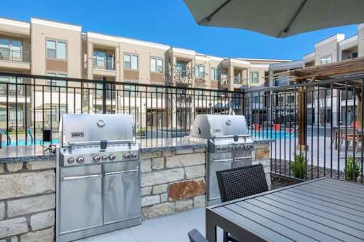 A BBQ grill is on a patio next to a pool.