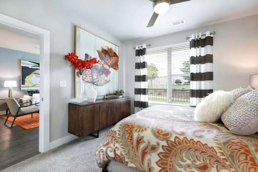 A bedroom with a bed, a chair, and a painting on the wall.