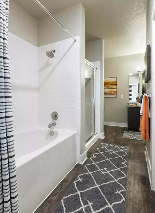 A bathroom with a white tub and a black and white striped shower curtain.