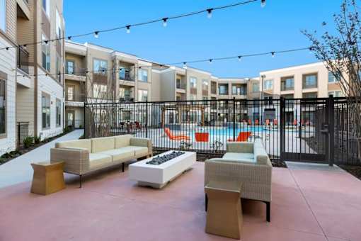 A patio area with furniture and a pool in the background.