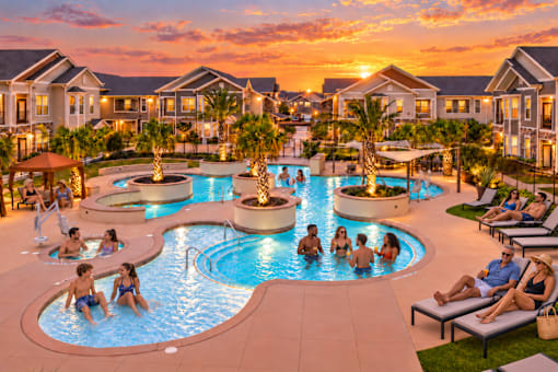 A group of people are enjoying the outdoor pool area at a resort.