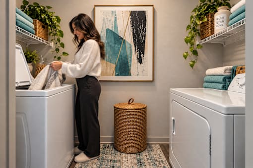 A woman is doing laundry in a room with a large artwork on the wall.