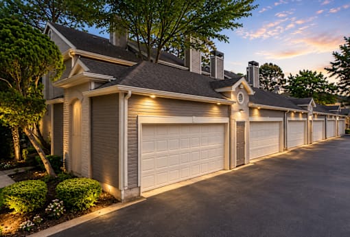 A row of houses with garages are shown at dusk.